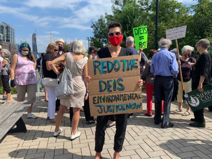 Nora Almeida holds a sign at a conference about the Gowanus rezoning