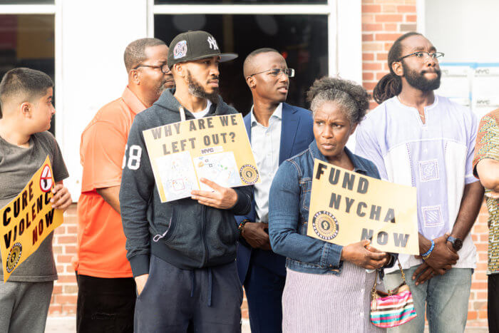 canarsie residents at rally hold signs that say "cure violence now" and "why are we left out?" at antiviolence rally