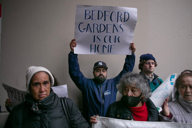 people holding signs at rally at bedford gardens