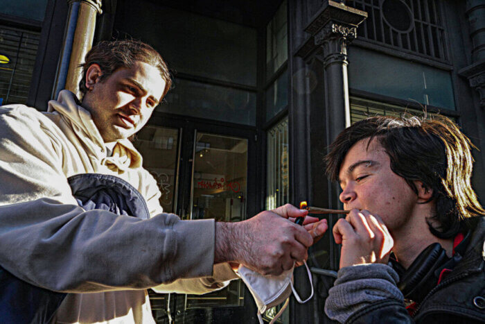 person lighting marijuana joint on sidewalk