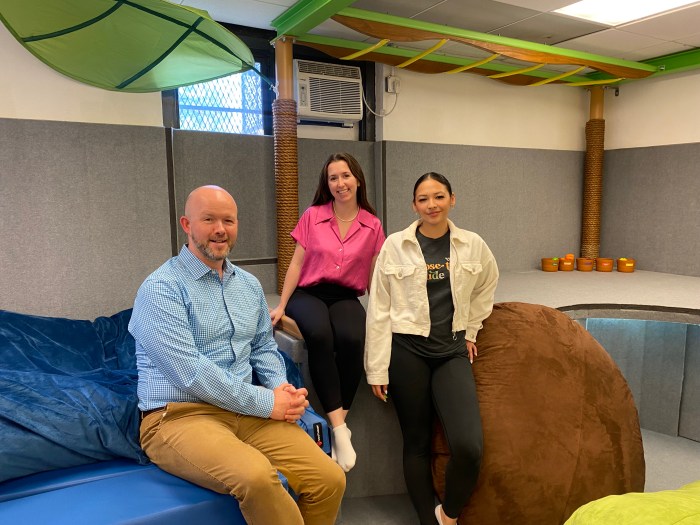 John H Linder Jr, Colleen O’Neill and Angelique Santos pose for a picture in the gym where the therapists work with students every day.